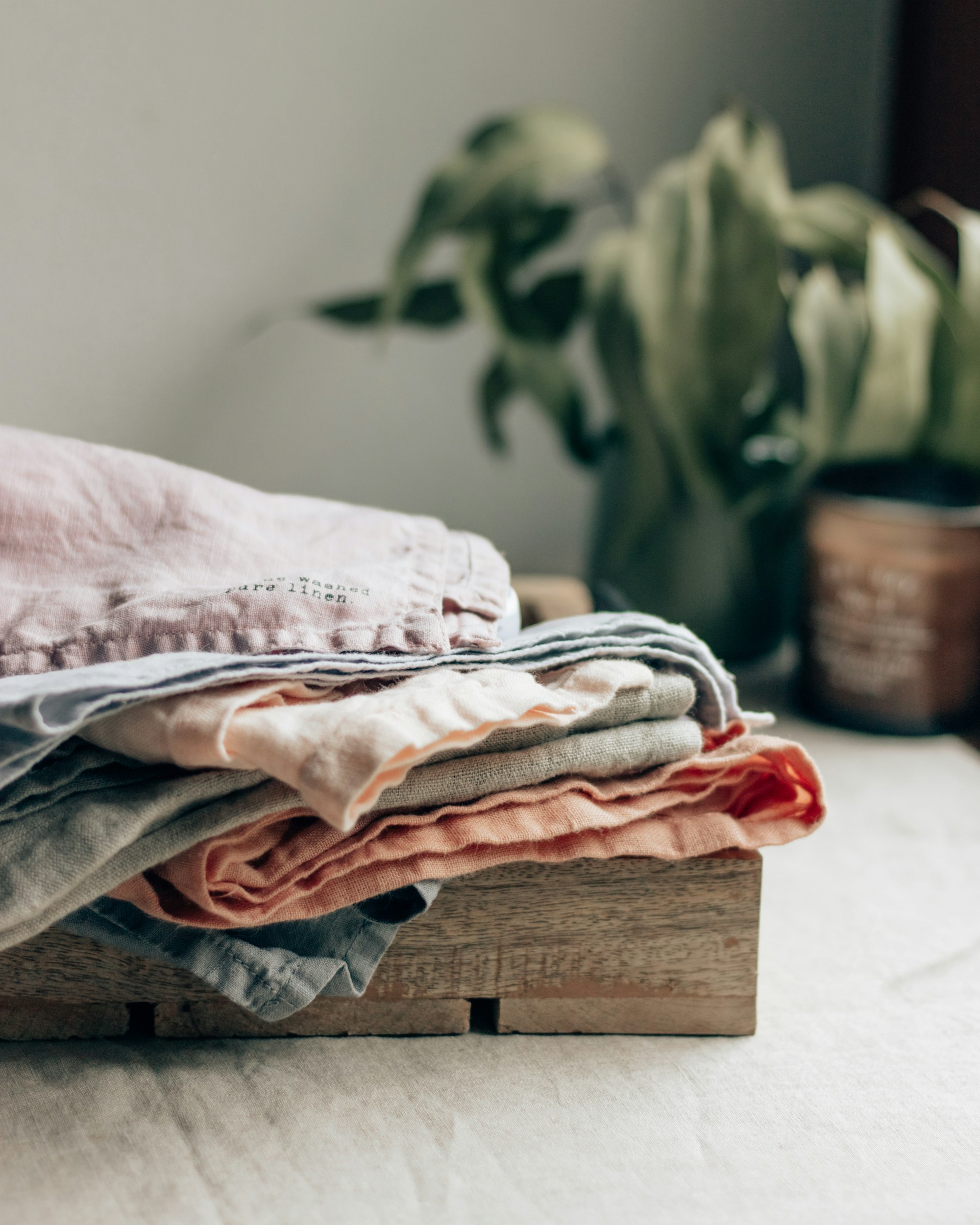 Folded linen pieces in dusty pink and cream on a wooden box